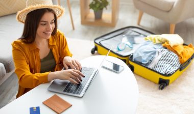 Happy young woman planning vacation travel with laptop pc