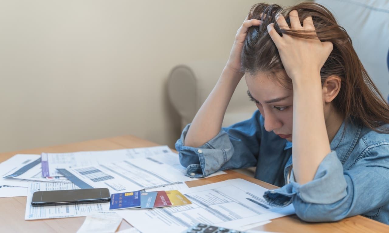 young asian woman cover her head after stressed with monthly bill expenses and credit card debt.