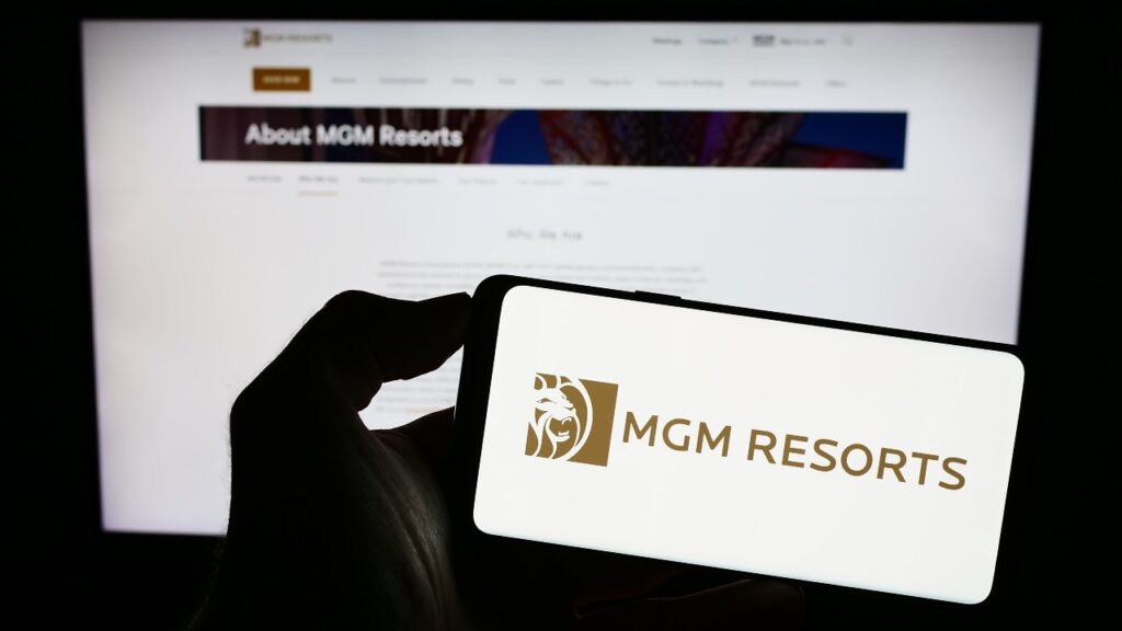 Person holding smartphone with logo of hospitality company MGM Resorts International on screen in front of website.