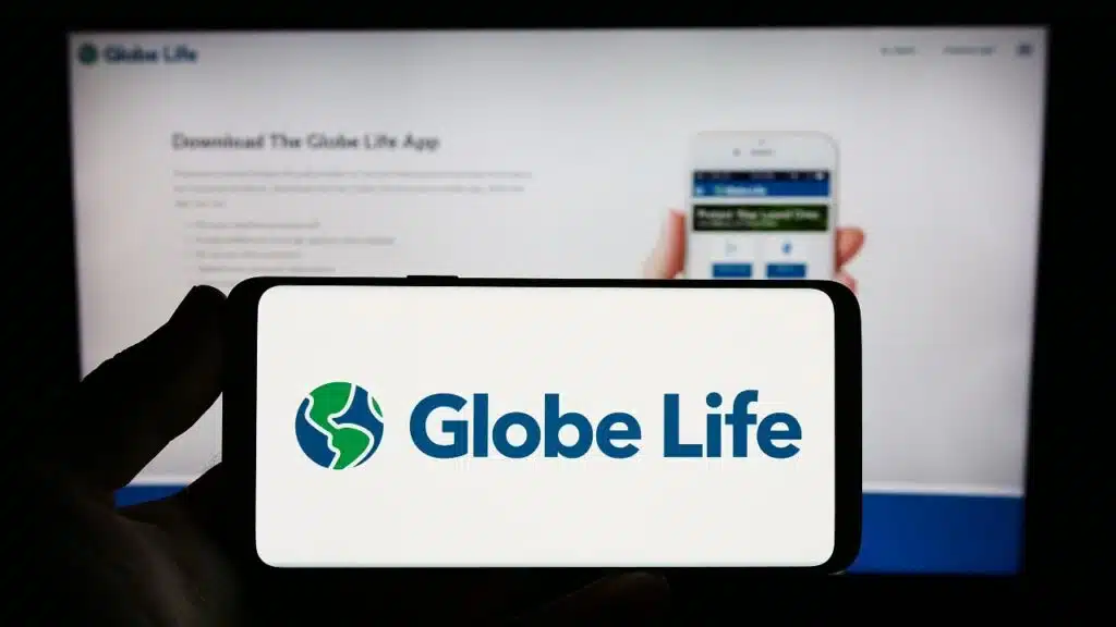 Person holding smartphone with logo of US insurance company Globe Life Inc. on screen in front of website.