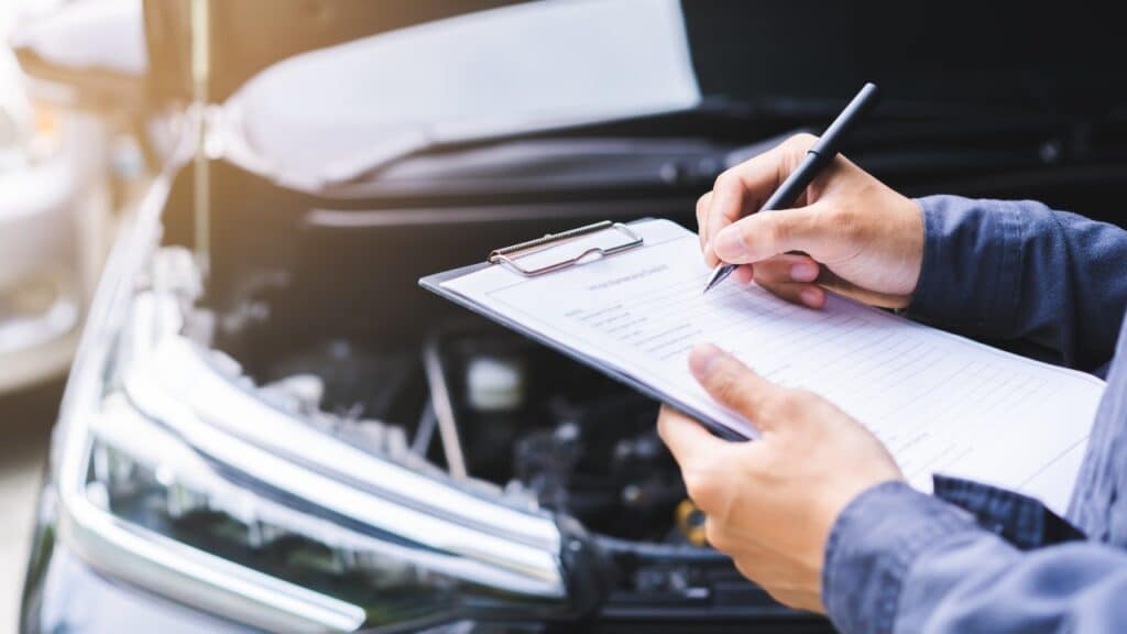 Auto check, car service shop concept. Automobile repairman writing job checklist on clipboard,