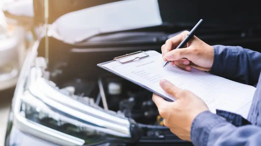 Auto check, car service shop concept. Automobile repairman writing job checklist on clipboard,