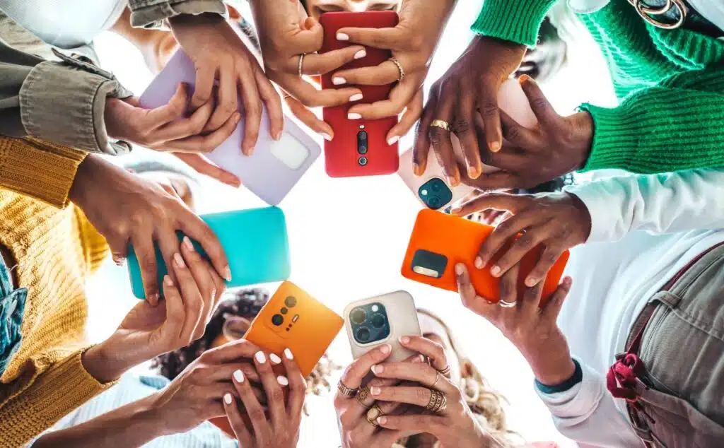 Group of young people using smart mobile phone device outside - Trendy technology concept with guys and girls on social media