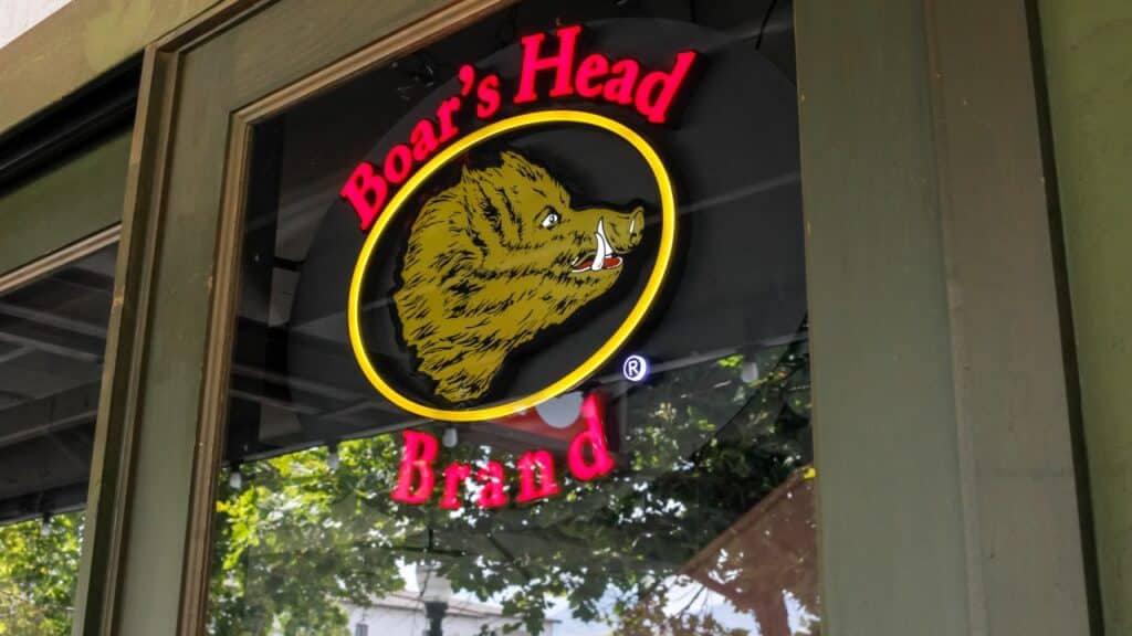 A view of a window sign advertising the availability of Boar's Head deli meat at a restaurant.