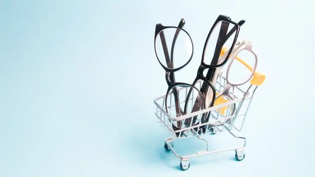 eyeglasses in a small shopping trolley, blue background, copy space, online buying glasses and eyeglass frames, online optics store.