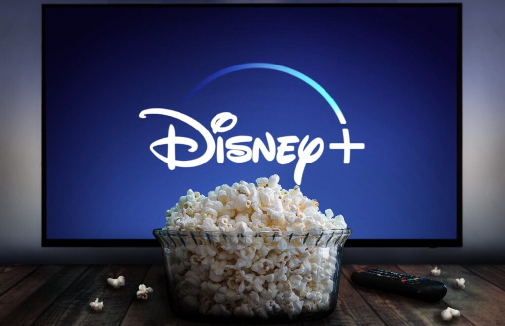 Disney+ app on tv screen behind a bowl of popcorn and a remote control.