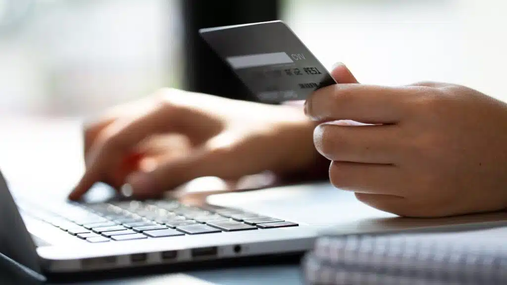 Close up woman hand using credit card and smartphone laptop for buying online shopping