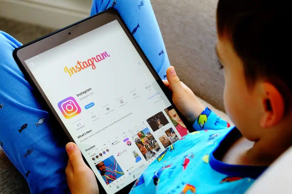 Child is holding device with instagram app in his hands.