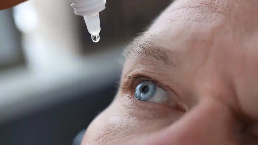 Man drips eye drops into eyes closeup.