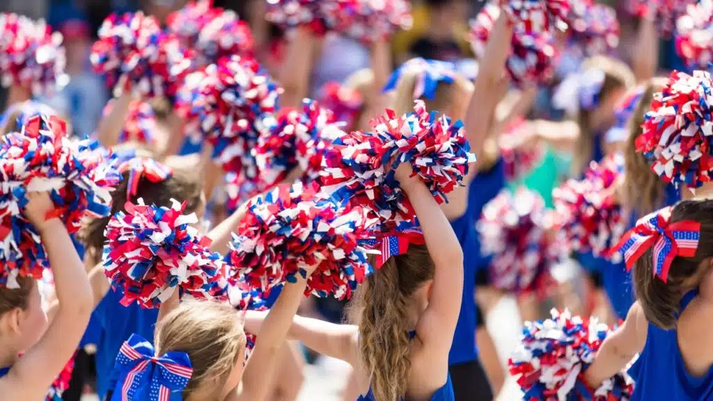 Cheerleaders Waving Red, White, and Blue Pom Poms, representing the Varsity Brands class action settlement
