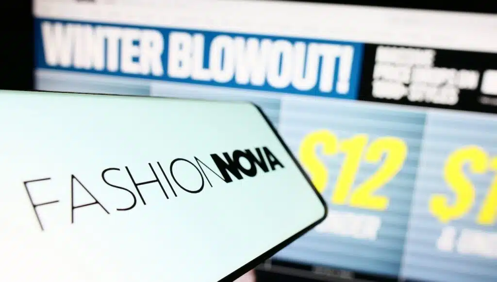Smartphone with logo of American e-commerce company Fashion Nova Inc. on screen in front of website.