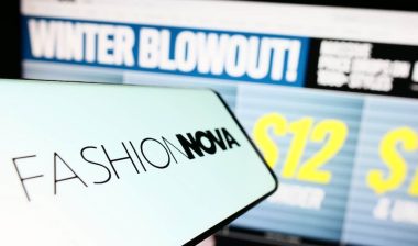 Smartphone with logo of American e-commerce company Fashion Nova Inc. on screen in front of website.