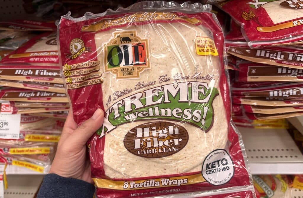 Hand holds up an Ole Mexican Foods Extreme Wellness keto high fiber tortillas