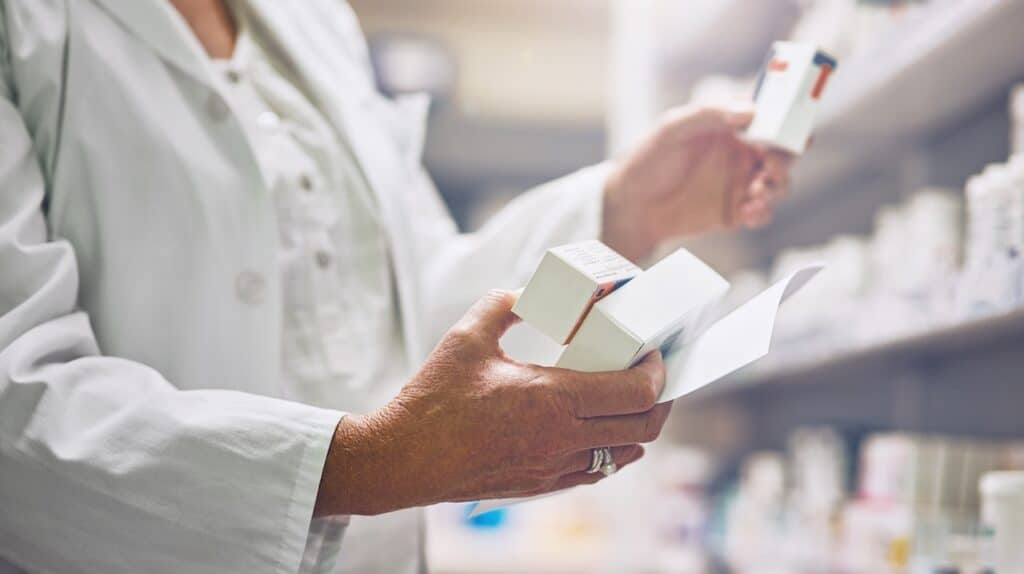 Pharmacist, hands and box for drugs with document at shelf for medicine, check and inventory for health.