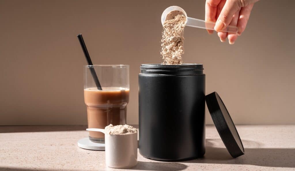 Protein shake and chocolate protein powder in a scoop, food supplement
