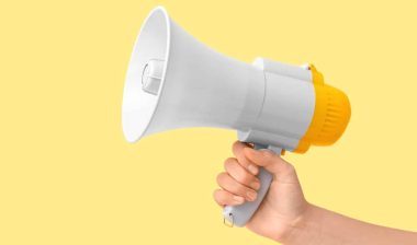 Female hand with megaphone on yellow background, representing the latest recalls in March 2025.