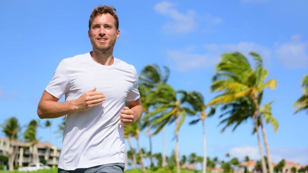 Healthy active man runner running in tropical park.