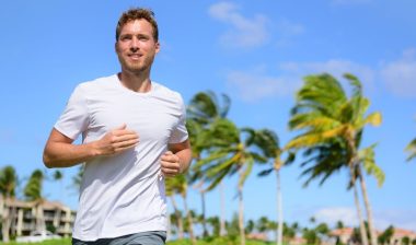 Healthy active man runner running in tropical park.