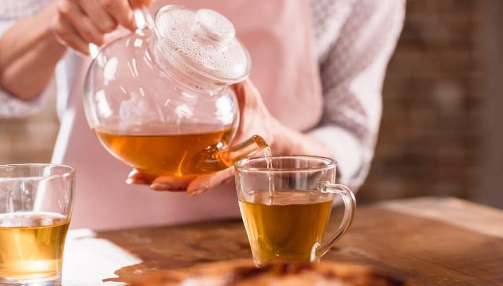 partial view of woman pouring hot tea in cup