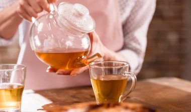 partial view of woman pouring hot tea in cup