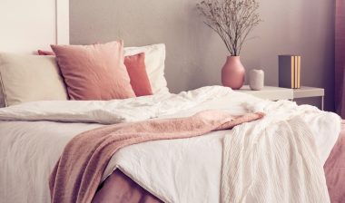 King size bed with pastel pink and white bedding in trendy bedroom