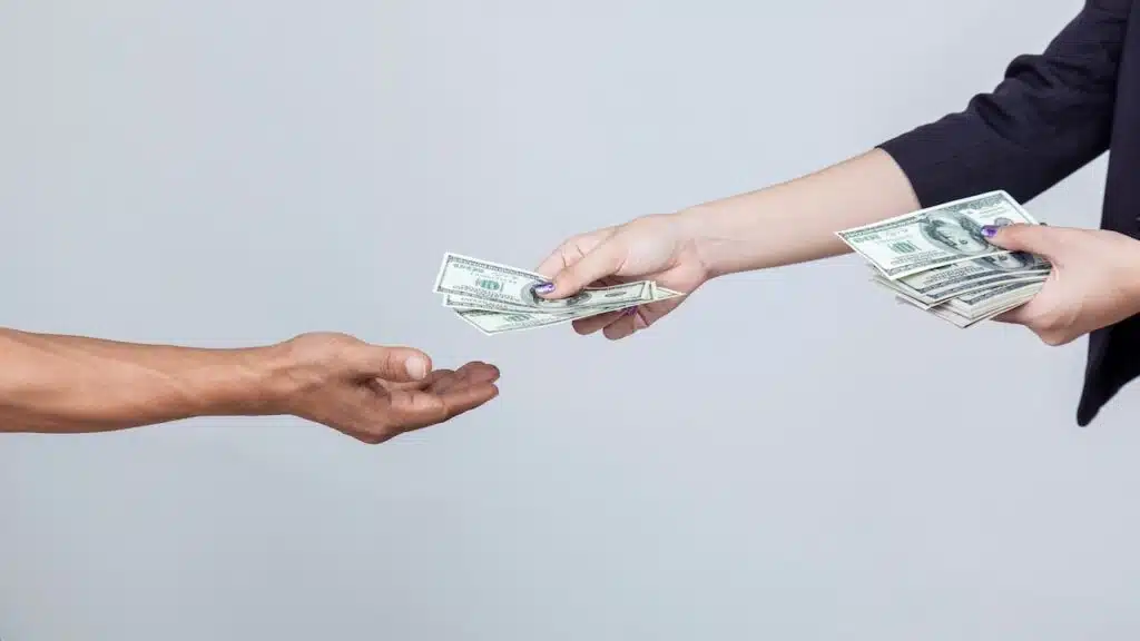 Woman's hand hold and send US dollar to another hand isolated on white background