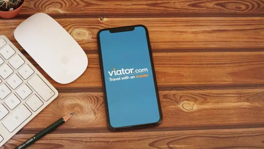 Viator App with Keyboard and Mouse on a Wooden Desk. Viator is a marketplace for tours, activities, and attractions.
