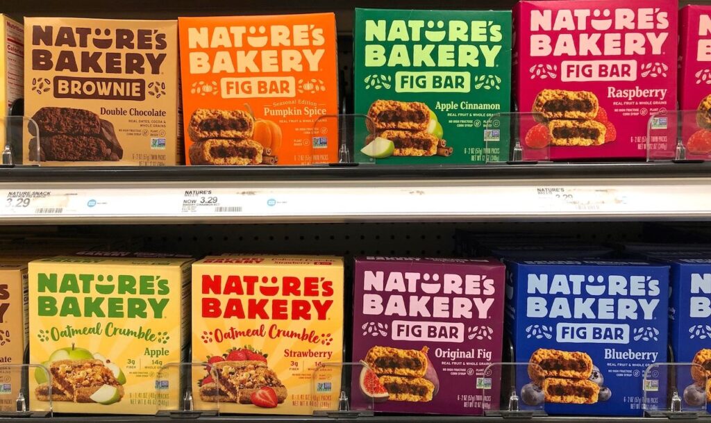 Grocery store shelf with boxes of Nature's Bakery brand fruit, fig and brownie bars in various flavors.