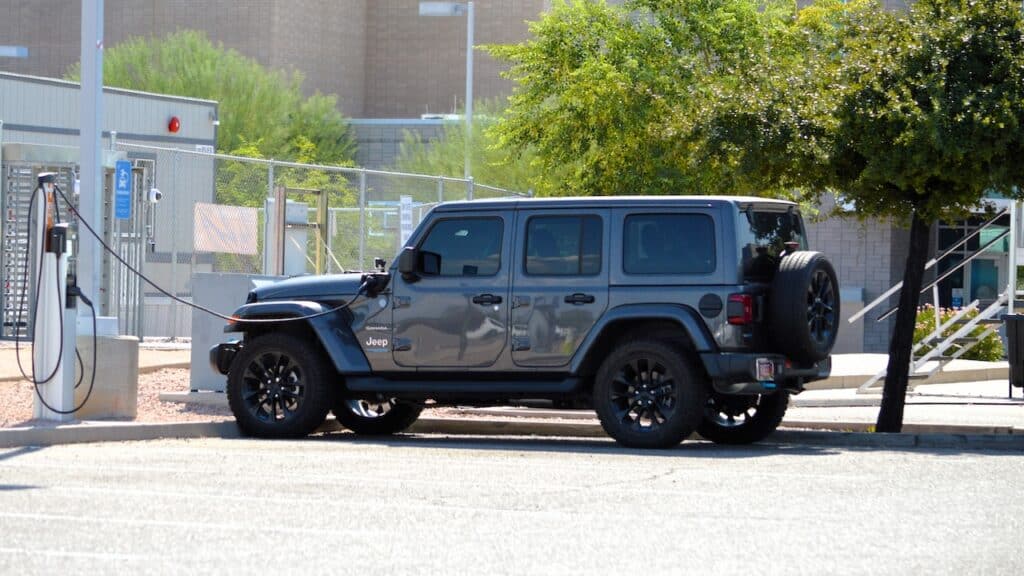 A Jeep Wrangler 4xe Sahara gas electric plug-in hybrid model charging at a ChargePoint EV station at an employee workplace.