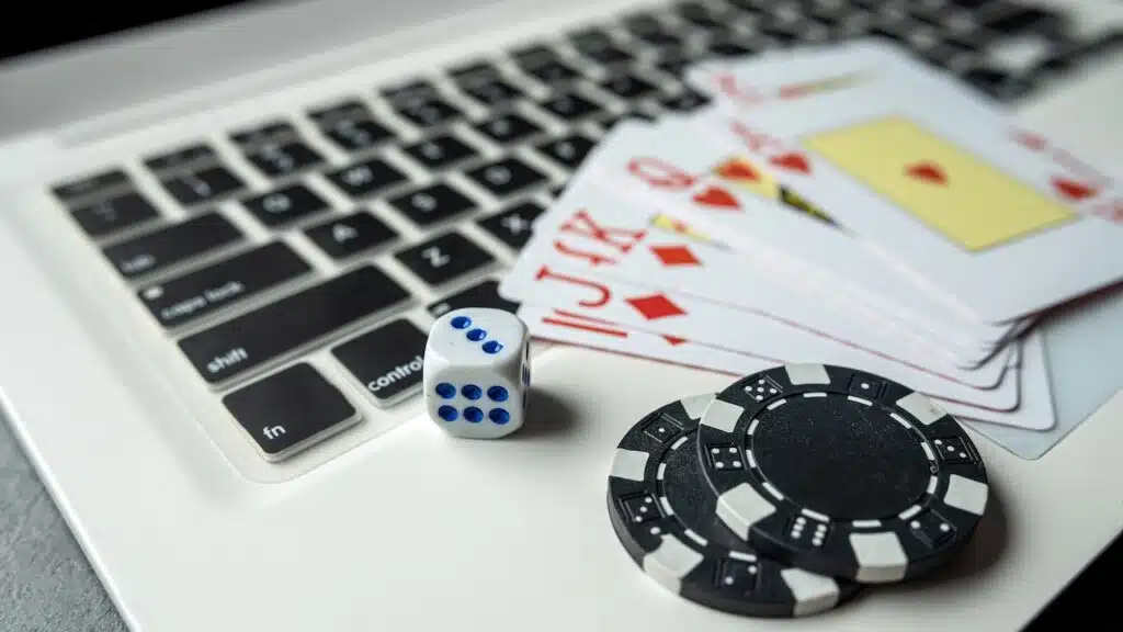 poker playing cards with casino chips on laptop keyboard for online gambling.