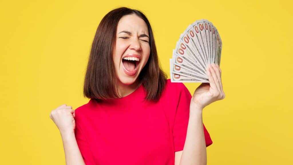 Young happy woman she wear pink t-shirt casual clothes hold in hand fan of cash money