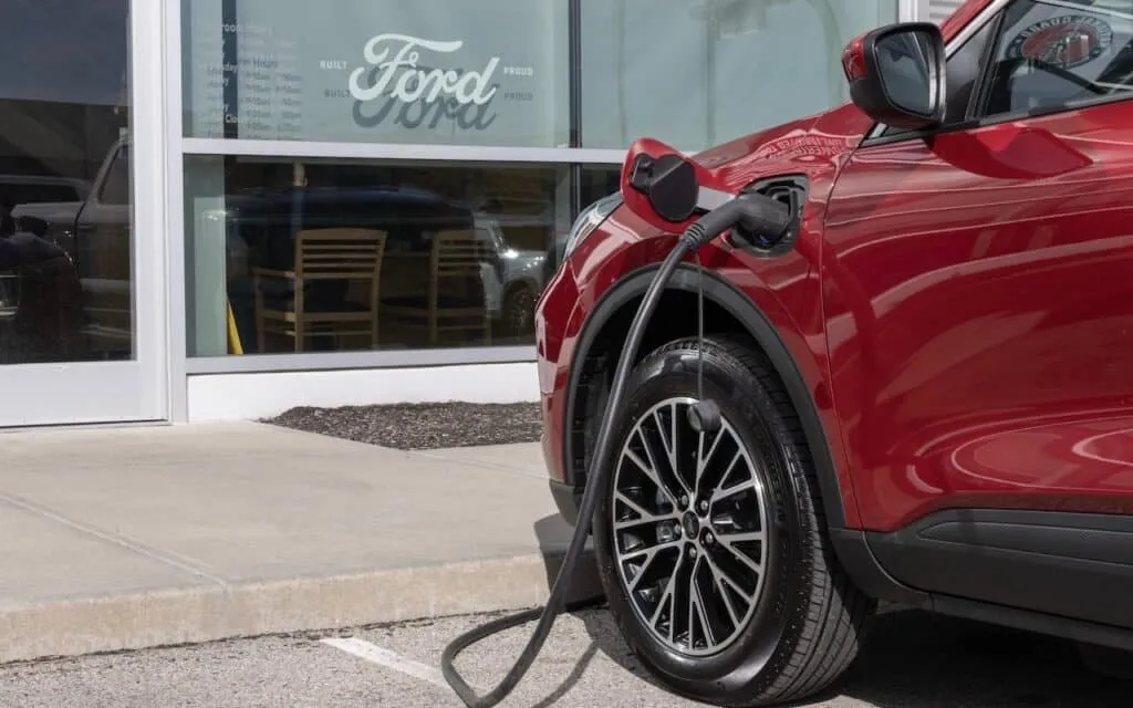 Ford Escape Base Hybrid SUV display at an EV charger.