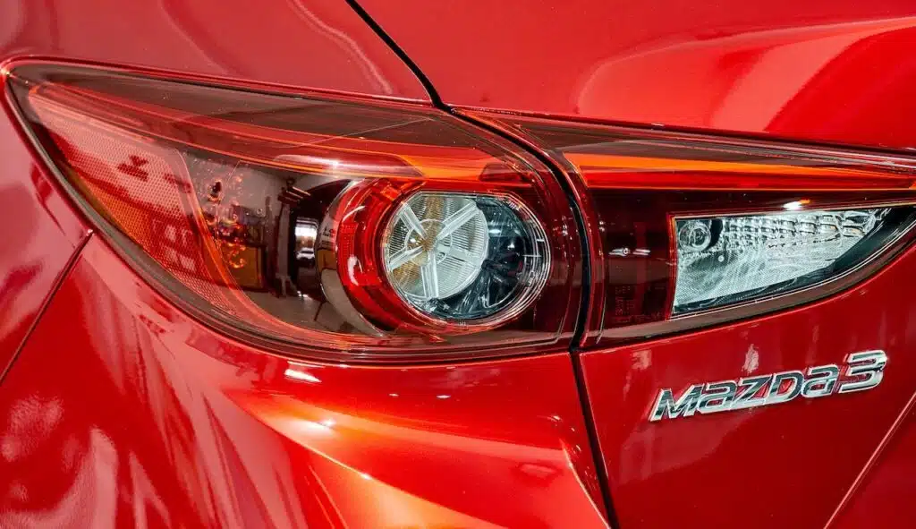 Taillight of Mazda 3 modern sporty hatchback with reflection on rear red paint after paint polishing and coating.