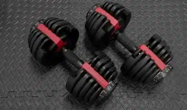 Adjustable weight dumbbells in plastic polymer material on black rubber floor.
