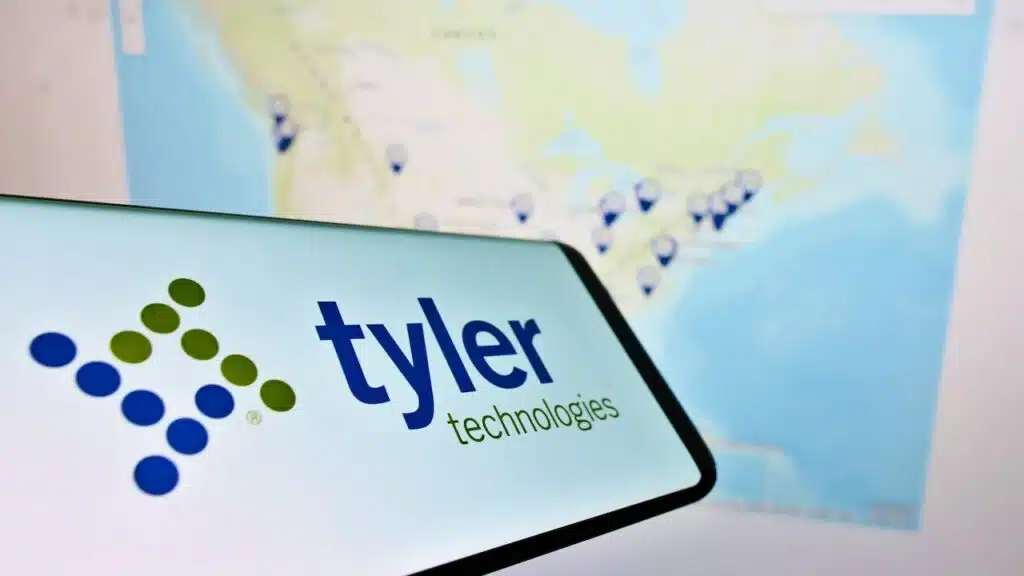 Smartphone with logo of American software company Tyler Technologies Inc. on screen in front of web site.