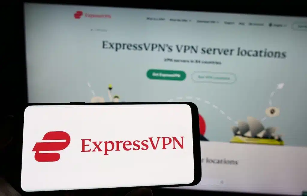 Person holding cellphone with logo of VPN service company ExpressVPN on screen in front of business webpage.