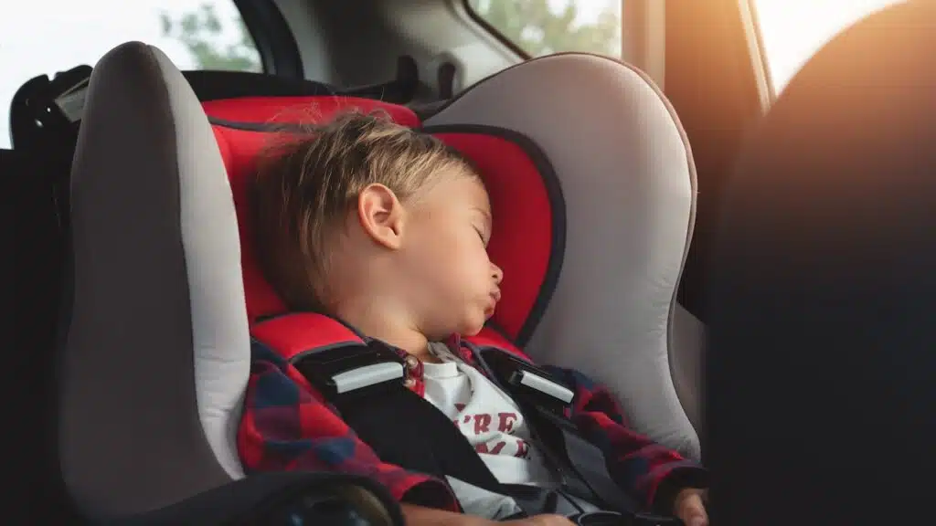 Adorable boy peacefully sleeping in a car seat inside a vehicle.