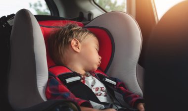 Adorable boy peacefully sleeping in a car seat inside a vehicle.