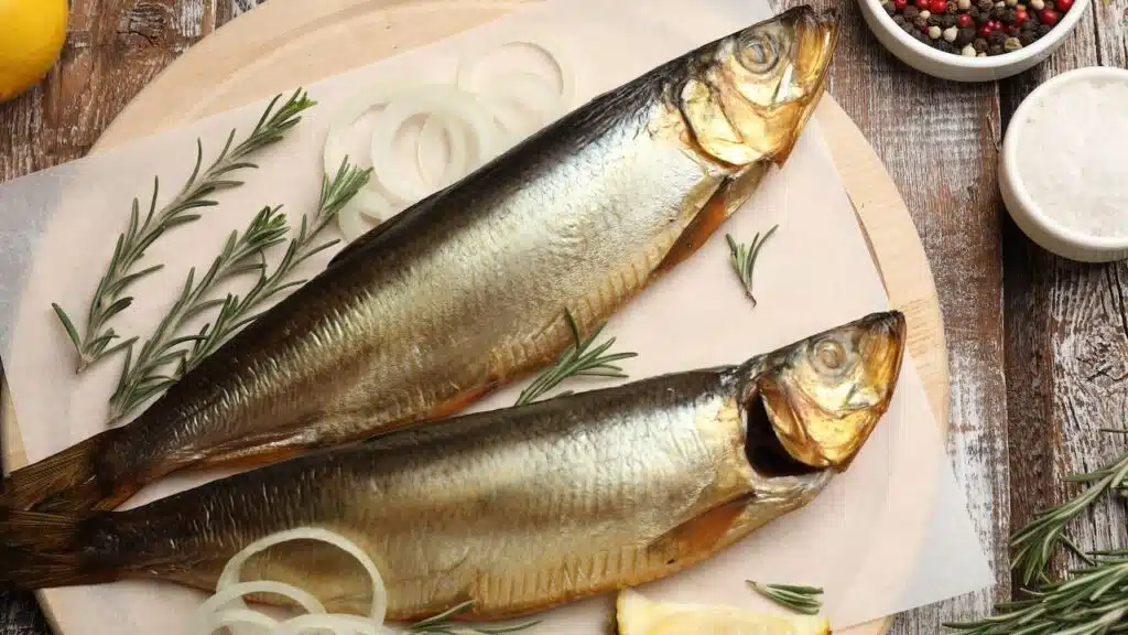 Smoked herrings and spices on wooden table