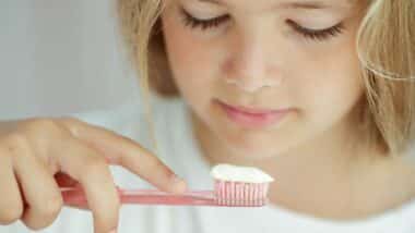 A young girl looking at toothpaste on a toothbrush, representing the Dr. Brite toothpaste class action lawsuit.