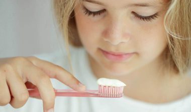 A young girl looking at toothpaste on a toothbrush, representing the Dr. Brite toothpaste class action lawsuit.