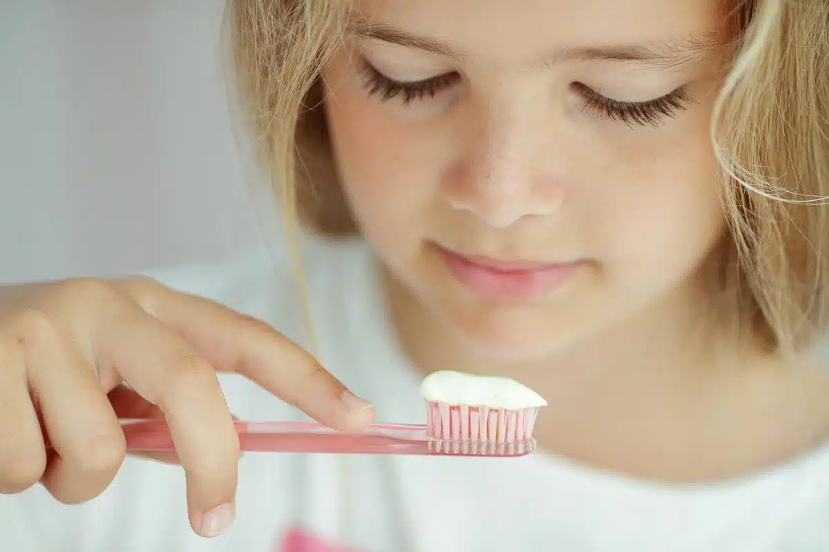 A young girl looking at toothpaste on a toothbrush, representing the Dr. Brite toothpaste class action lawsuit.