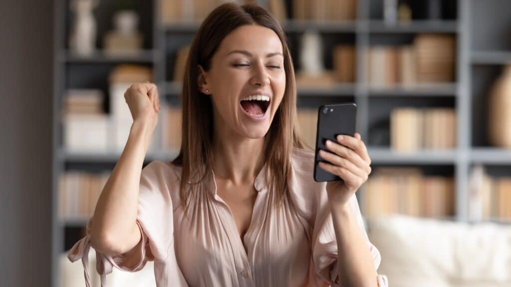 Close up overjoyed woman looking at phone screen about refunded money
