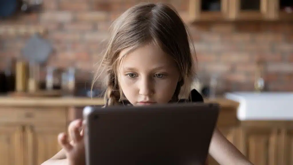 Focused gen Z little schoolkid using online app on tablet