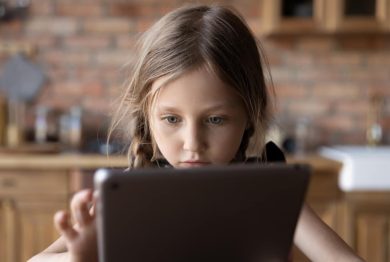 Focused gen Z little schoolkid using online app on tablet