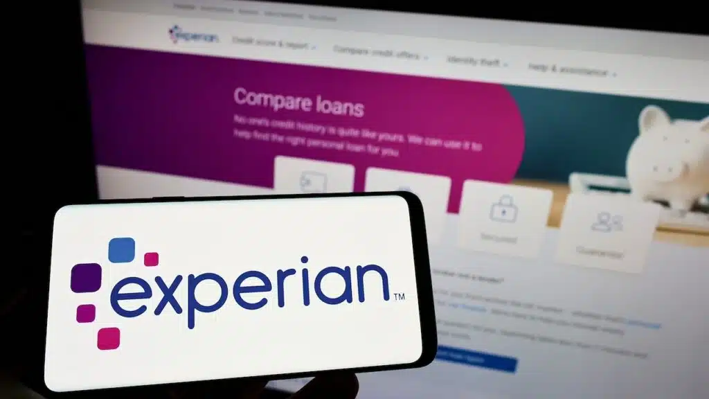 Person holding smartphone with logo of credit reporting company Experian plc on screen in front of website. Focus on phone display. Unmodified photo.