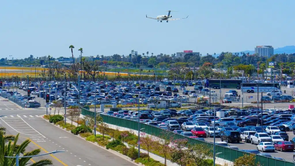 Packed LAX Parking with a plane coming in for landing.