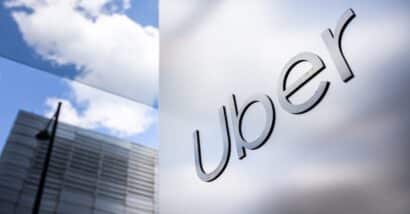 Uber logo on a sleek, reflective wall with urban high-rises in the background, representing modern transportation and technology innovation. Uber headquarters offices
