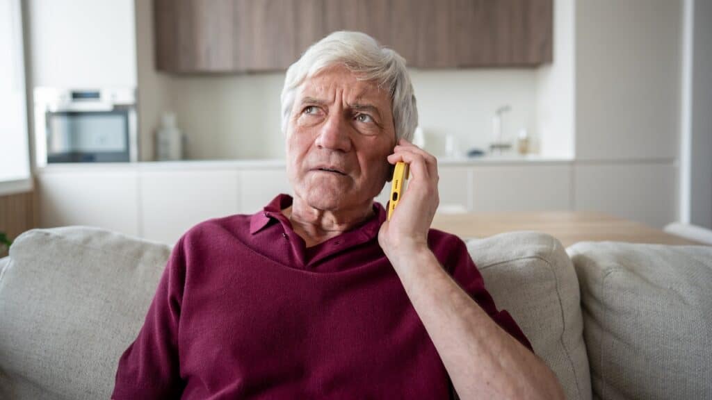 Distrustful and anxious senior man frowns during unwanted call