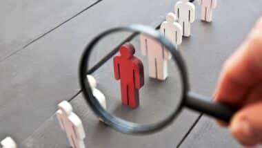 The view through the magnifier on the one wooden red person between other people